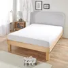 A white fitted sheet on a wooden bed frame in a bedroom setting.