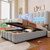 A modern bedroom with a bed that has its storage compartment open, revealing stored items. The bed features LED lighting in the headboard. Náhled obrázku produktu