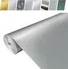 A roll of metallic wallpaper or material with a brushed silver finish, with smaller samples of different metallic finishes visible in the background. Produktbild-Vorschau