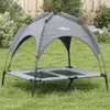 A dog bed with a canopy is set up on a grassy lawn in front of a wooden fence and some bushes. Náhled obrázku produktu