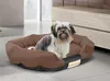 A small dog sits in a brown and black dog bed in a room. Anteprima dell’immagine prodotto