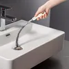 A hand is using a drain cleaning brush to clean a sink drain. Produktbild-Vorschau