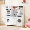 A white toy kitchen set with various appliances and accessories, set up in a room with a rug and wall art. Náhled obrázku produktu