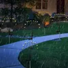 Solar garden lights shaped like fireflies are illuminating a pathway and lawn at night during a rain shower. Produktbild-Vorschau