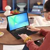 A person is using a tablet with a keyboard case on a wooden table, with decorative items in the background. Anteprima dell’immagine prodotto