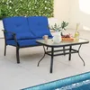 An outdoor patio setting with a blue cushioned loveseat and a glass-topped coffee table next to a pool. Podgląd zdjęcia produktu