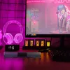 A desk setup with a computer monitor, headphones, and a soundbar, all illuminated by purple lighting. Produktbild-Vorschau