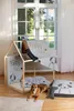 A dog is lying on a rug in front of a wooden dog house, surrounded by dog accessories. Produktbild-Vorschau