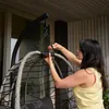 A woman is assembling a hanging chair on a porch. Produktbild-Vorschau