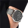 A close-up shot of a man's wrist wearing a silver Armani watch with a dark gray dial. Náhled obrázku produktu