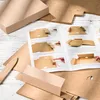 An instruction manual and unassembled cardboard boxes are laid out on a white wooden surface. Produktbild-Vorschau