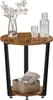 A round side table with a wood-look top and black metal legs, featuring a vase with flowers, a glass, and a bottle on top, and a basket with magazines on the lower shelf. Produktbild-Vorschau