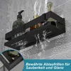 A black shower shelf with bottles of toiletries on it, with water spraying over it to demonstrate drainage. Anteprima dell’immagine prodotto
