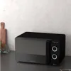 A black microwave oven is placed on a countertop in a kitchen setting. Anteprima dell’immagine prodotto