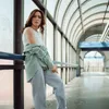 A woman leans against a railing in a modern, covered walkway. Anteprima dell’immagine prodotto