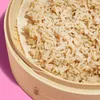 A close-up shot of cooked brown rice in a bamboo steamer. Produktbild-Vorschau
