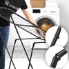 A person is shown folding a black drying rack in a laundry room with a washing machine in the background. Podgląd zdjęcia produktu
