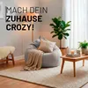 A cozy living room scene with a large beanbag chair, a small wooden table, and plants. Voir les images du produit