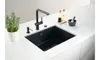 A black kitchen sink with a black faucet and accessories on a white countertop. Podgląd zdjęcia produktu