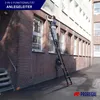 A person is using a multi-purpose ladder against the side of a brick building. Produktbild-Vorschau