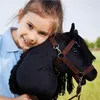 A young girl hugging a black hobby horse in a grassy field. Anteprima dell’immagine prodotto