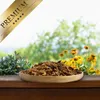 A wooden bowl filled with dried insects sits on a wooden surface, with lush green foliage and yellow flowers in the background. A golden banner with the word 'PREMIUM' and stars is overlaid in the top left corner. Produktbild-Vorschau