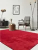 A modern living room with a red rug, armchair, side table, and abstract art. Produktbild-Vorschau