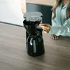 A person is using a coffee maker on a wooden table. Anteprima dell’immagine prodotto