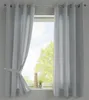 Two light gray curtains are shown hanging in front of a window. The left curtain is tied back with a fabric tie. A small potted plant and a decorative item are on the windowsill. Produktbild-Vorschau
