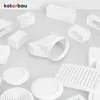 A collection of white ventilation components, including rectangular connectors, round vents, and grilles, arranged on a light gray surface. Voir les images du produit