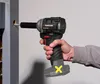 A hand holding a cordless impact wrench, driving a screw into a wooden post. Anteprima dell’immagine prodotto
