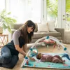 A mother is playing with her baby on a playmat in a living room. Produktbild-Vorschau