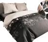A close-up view of a bed with a duvet cover featuring a dark floral pattern and two beige pillows. Produktbild-Vorschau
