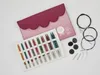 A set of interchangeable circular knitting needles and accessories laid out on a white background, with a pink and burgundy case in the background. Produktbild-Vorschau