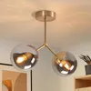A close-up shot of a modern, two-light ceiling lamp with gold metal accents and clear glass globes. Produktbild-Vorschau