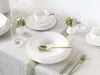 A table setting with white porcelain dishes, gold cutlery, and a wine glass. Náhľad obrázku produktu