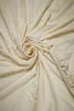 A cream-colored fitted sheet is laid out and swirled in the center, with the elasticized edge visible on the right side. Produktbild-Vorschau