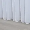 A close-up view of the bottom edge of white sheer curtains hanging over a light gray floor. Produktbild-Vorschau
