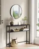 A narrow console table with two shelves, decorated with a lamp, books, and a basket, placed in a hallway next to a door and window. Náhled obrázku produktu