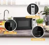 A black microwave oven is shown on a kitchen counter, with close-up insets highlighting its digital controls, interior light, and grill rack. Produktbild-Vorschau