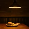 A hamburger and fries are presented on a wooden table under a pendant lamp. Produktbild-Vorschau