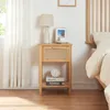A bedside table with a lamp, picture frame, and books next to a bed. Produktbild-Vorschau