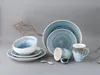 A set of blue and white stoneware dishes and mugs arranged on a plain gray background with a dried branch. Náhľad obrázku produktu