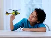 A young boy is holding a toy helicopter and looking at it with a smile. Anteprima dell’immagine prodotto
