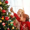 A mother and daughter decorating a Christmas tree with ornaments. Produktbild-Vorschau