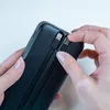 Hands holding a black power bank with integrated USB-C and Lightning cables. Anteprima dell’immagine prodotto