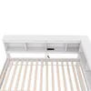 Close-up view of the headboard of a white bed frame with built-in shelves and charging ports. Podgląd zdjęcia produktu
