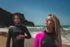 A man and a woman in wetsuits on a beach. Náhľad obrázku produktu