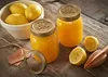 Two jars of lemon curd with lemons and a wooden juicer on a wooden table. Voir les images du produit