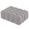 A gray upholstered ottoman or footstool with a tufted, segmented design. Náhľad obrázku produktu